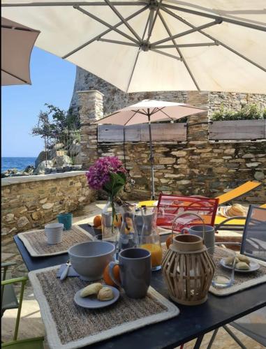 un tavolo con cibo e un ombrellone su un patio di Casa Torra d'Erbalunga a Brando