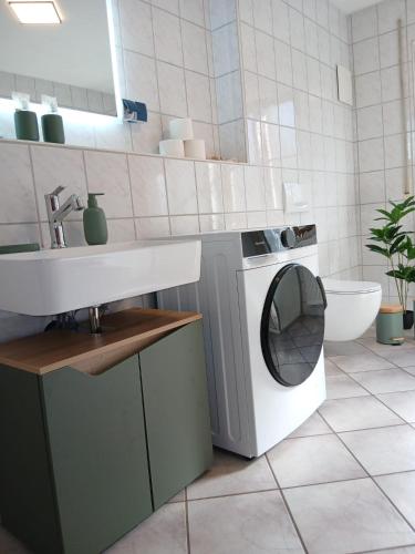a bathroom with a washing machine and a sink at Savor Appartement Bergblick für 6 Personen in Sohland