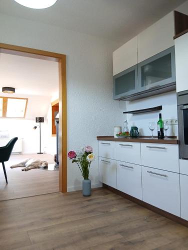 a kitchen with white cabinets and a vase of flowers at Savor Appartement Bergblick für 6 Personen in Sohland