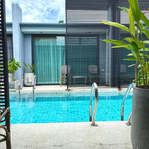 a swimming pool with chairs next to a house at Xen Pool Access in Chalong 