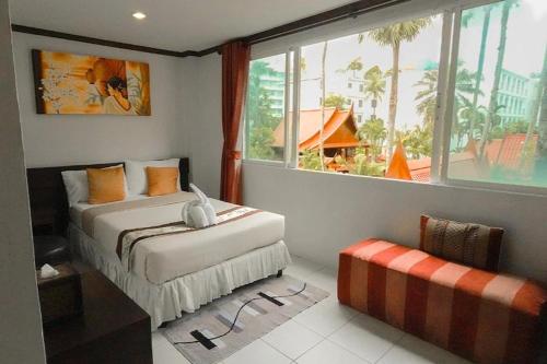 a bedroom with two beds and a large window at The Nice Patong Hotel in Patong Beach