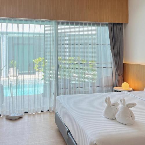 two rabbits sitting on a bed in a bedroom at Xen Pool Access in Chalong 