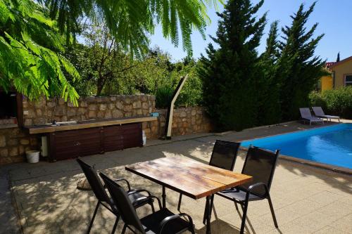 una mesa de madera y sillas junto a una piscina en Apartments Sunny, en Karlobag