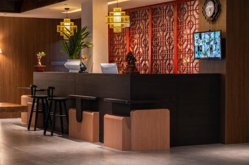 a restaurant with a bar with stools and a clock at YiQuan RIVERVIEW B&B in Fenghuang