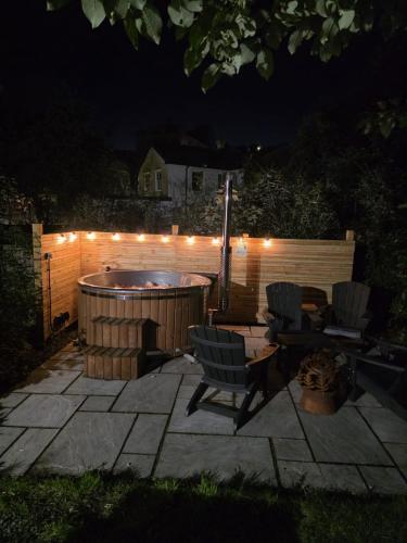 a backyard patio with a hot tub and chairs at night at Modern 2 bedroom cottage near Bike Park Wales. in Merthyr Tydfil