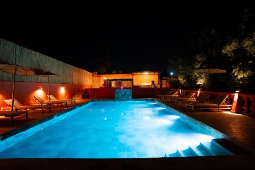 a swimming pool at night with chairs and umbrellas at Villa Marrakchia - Palais d'hôtes & spa in Marrakech