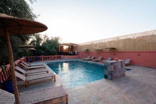 a swimming pool with chairs and an umbrella at Villa Marrakchia - Palais d'hôtes & spa in Marrakech