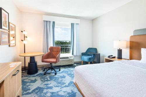 a hotel room with a bed and a desk and a window at Hampton Inn Lawrenceville Duluth in Lawrenceville