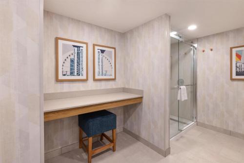 a bathroom with a walk in shower and a vanity with a blue stool at Hampton Inn Lawrenceville Duluth in Lawrenceville