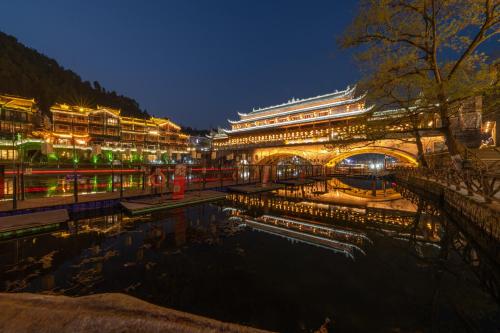 a building with a pond in front of it at night at YiQuan RIVERVIEW B&B in Fenghuang