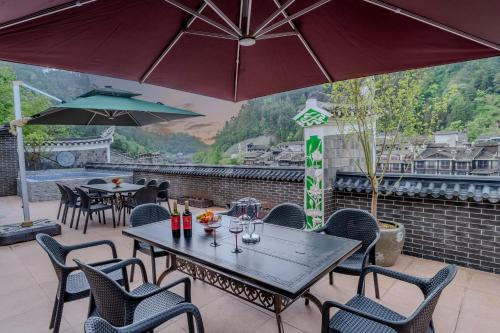 a patio with tables and chairs and umbrellas at YiQuan RIVERVIEW B&B in Fenghuang
