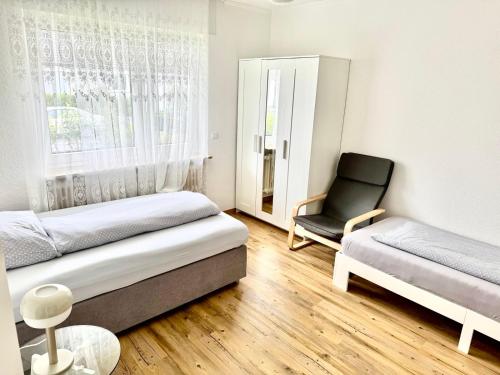 a room with two beds and a chair in it at Haus Schwarzwald - Bad Krozingen in Bad Krozingen