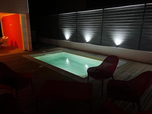 a swimming pool with two chairs and a table at Villa Timoun - Standing - 3 ch in Quartiers Anse à lʼÂne
