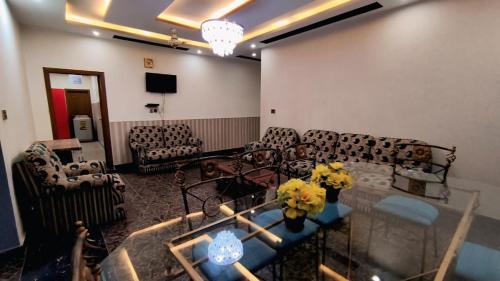 a living room with couches and a table with flowers on it at Star Guest House in Jhelum