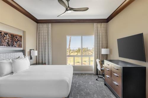 a hotel room with a bed and a flat screen tv at Hilton Grand Vacations Club Kohala Suites Waikoloa in Waikoloa
