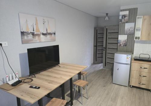 a room with a table with a television and a kitchen at TESTkg in Cholpon-Ata