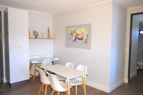 a dining room with a table and white chairs at iKON Self-Catering in Windhoek