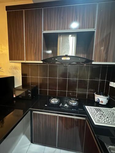 a kitchen with a black stove and brown cabinets at Effa Homestay in Sungai Petani