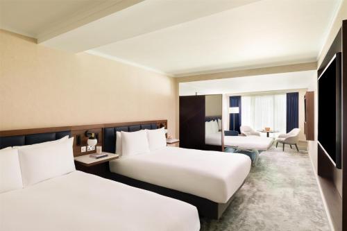 a hotel room with two beds and a desk at Hilton London Metropole in London