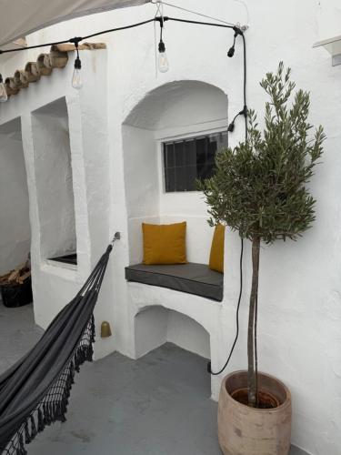 a porch with a bench and a potted plant at Casa Entre Lunas - Stylish Rustic Retreat in Olvera