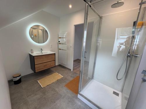 ein Badezimmer mit Dusche, Waschbecken und Spiegel in der Unterkunft Maison Soulom in Soulom