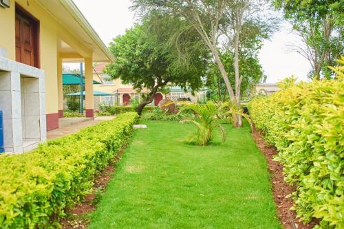 a yard with green grass and bushes next to a house at Cheerful 4-bedroom with pool in Athi River