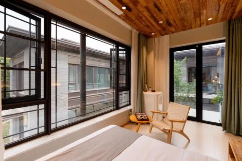 a bedroom with large windows and a bed and a chair at Lu Ming Beiyuan Xi'an Zhongdu Drum Tower City Wall Store in Xi'an