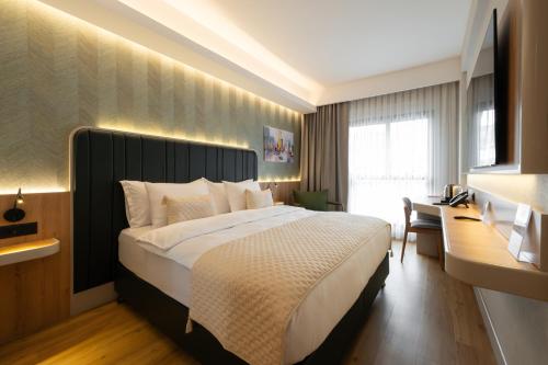 a bedroom with a large bed and a desk at Alves Hotel in Konak