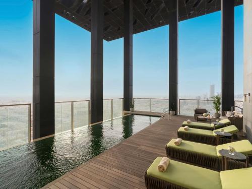 a pool with chaise lounges and chairs in a building at Fairmont Ramla Serviced Residences in Riyadh