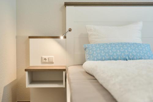 a bed with a blue pillow next to a night stand at Kanalkajüte Theodor in Hanerau-Hademarschen