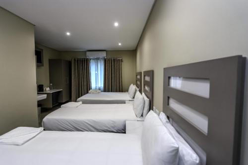 une chambre d'hôtel avec deux lits et une salle de bain dans l'établissement PLM Palace Lodge, à Durban