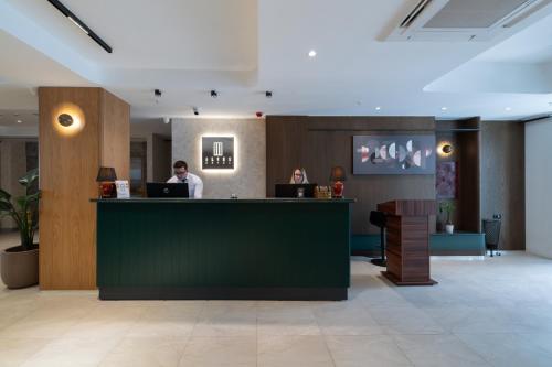 a man sitting at a counter in a lobby at Alves Hotel in Konak