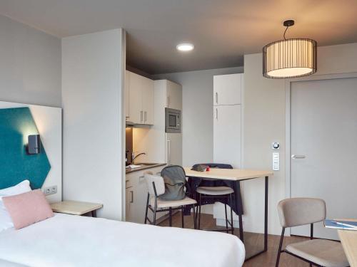 a bedroom with a bed and a table and chairs at Aparthotel Adagio Paris Suresnes Longchamp in Suresnes