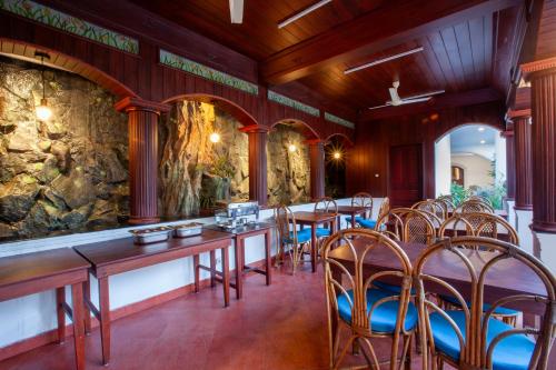 a restaurant with tables and chairs and a stone wall at Villa Elixir Fort Kochi in Cochin