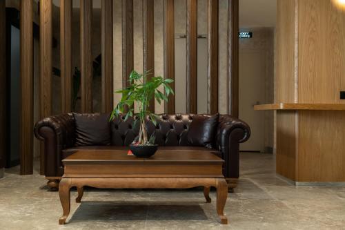 a brown leather couch with a potted plant on a coffee table at Alves Hotel in Konak