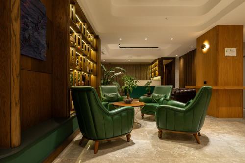 a lobby with green chairs and a table at Alves Hotel in Konak