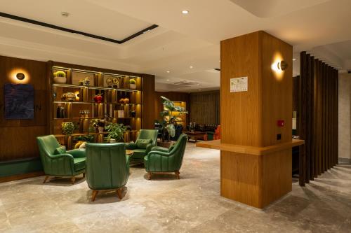 a waiting room with green chairs and shelves at Alves Hotel in Konak