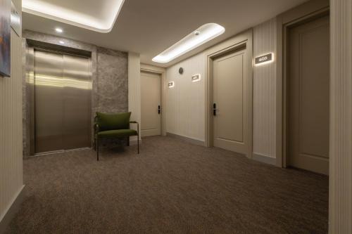 an office hallway with a green chair and doors at Alves Hotel in Konak