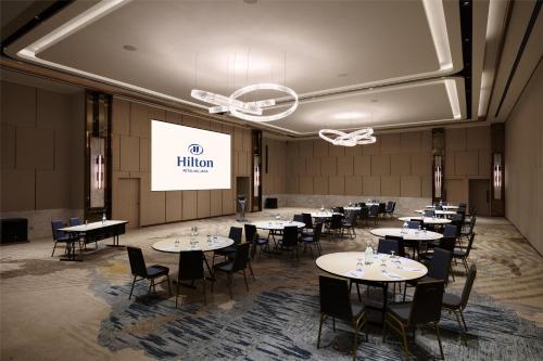 a conference room with tables and chairs and a screen at Hilton Petaling Jaya in Petaling Jaya