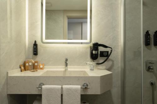 a bathroom with a sink and a mirror at Alves Hotel in Konak