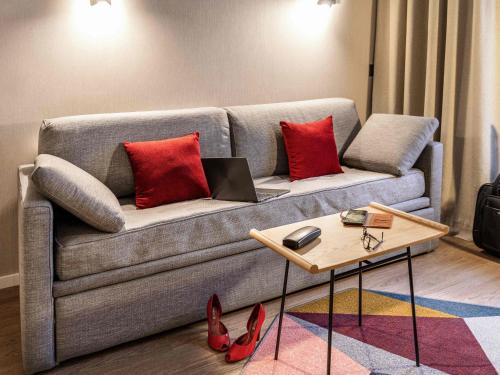 a living room with a couch with red pillows and a table at Aparthotel Adagio Zurich City Center in Zurich