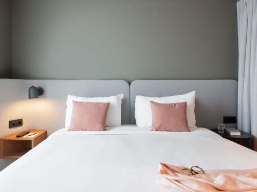 a bedroom with a white bed with pink pillows at Aparthotel Adagio Zurich City Center in Zurich