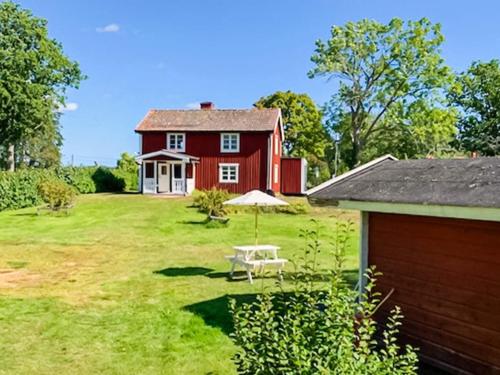 a red house with a table and an umbrella in the yard at 5 person holiday home in LOFTAHAMMAR-By Traum in Loftahammar