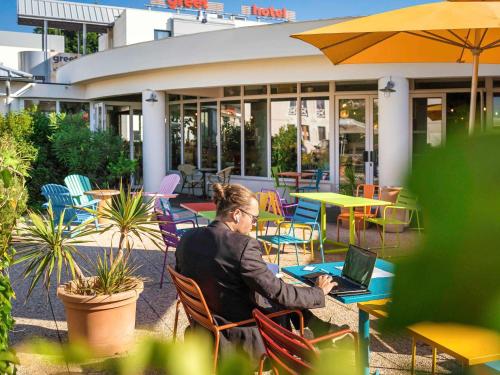 a man sitting at a table with a laptop at greet Hotel Bordeaux Aeroport in Mérignac