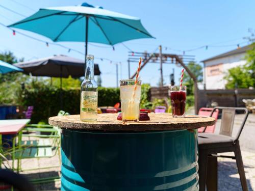 a table with drinks on top of a barrel with an umbrella at greet Hotel Bordeaux Aeroport in Mérignac