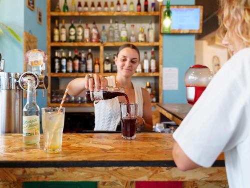 a woman is making a drink at a bar at greet Hotel Bordeaux Aeroport in Mérignac