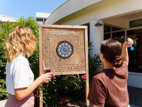 two women standing in front of a sign with a clock at greet Hotel Bordeaux Aeroport in Mérignac