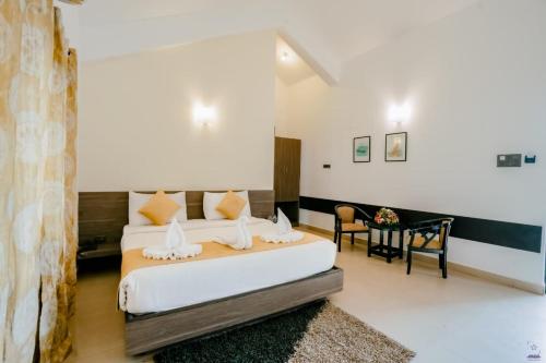 une chambre avec un lit, une table et des chaises dans l'établissement Mint By SR, à Calangute