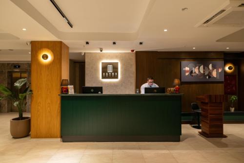 a man sitting at a counter in a hotel lobby at Alves Hotel in Konak