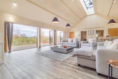 a living room with white furniture and large windows at White House Lodges - Napier in Heveningham
